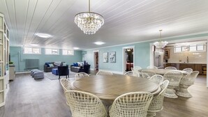 A spacious room with a round wooden table surrounded by wicker chairs, a chandelier, and a view of the kitchen. - McKinley Mansion Full Building w/Bball gym, Arcades, 13000 sqft, Sleeps 70.  (Pocatello)