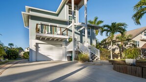 A modern two-story house with a garage, a balcony, and a staircase leading to the upper floor. - Winter Getaway by the Bay. Direct Water View! Near Marco Island Beaches. (Naples)