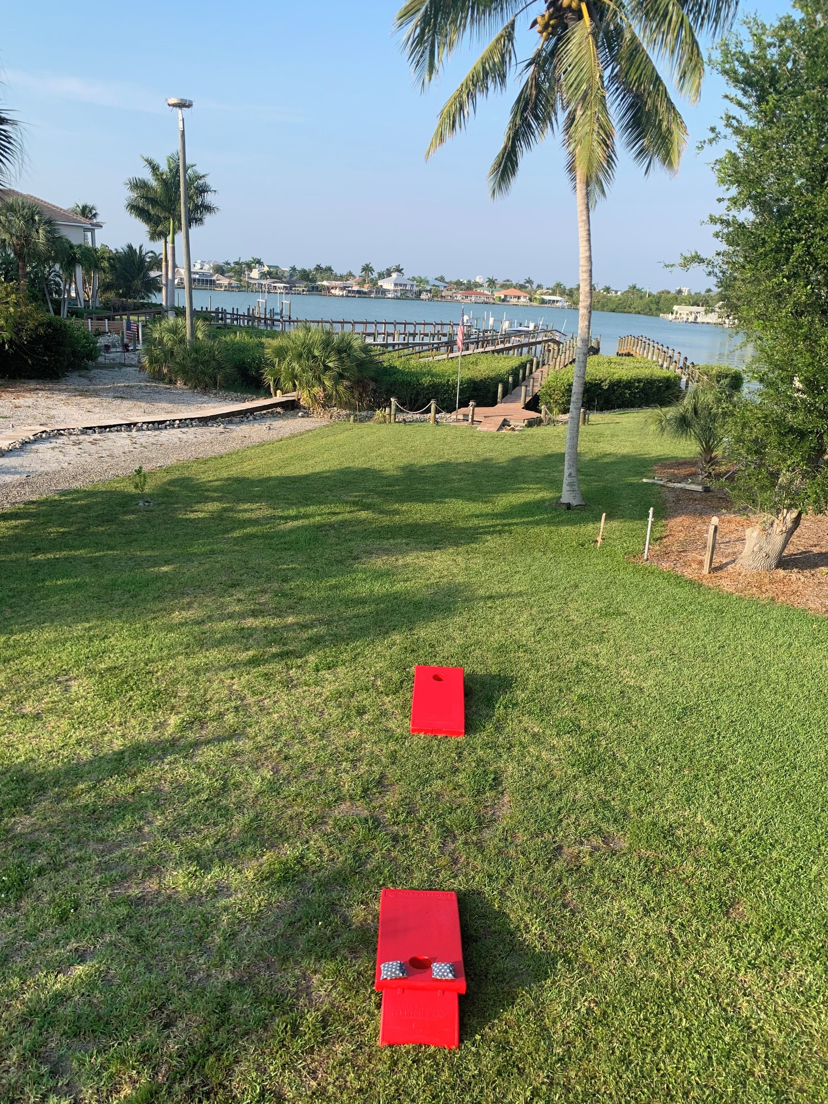 A grassy area with two red objects, a wooden dock, and a body of water in the background.