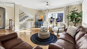 A spacious living room with a brown leather sofa, a round coffee table, and a staircase leading to another level. - Winter Getaway by the Bay. Direct Water View! Near Marco Island Beaches. (Naples)