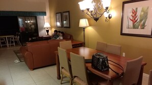 A dining area with a wooden table, wicker chairs, and a brown leather sofa. - Westgate Vacation Villas Resort (Kissimmee)
