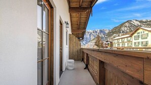 A wooden balcony with large windows overlooking a mountain landscape.