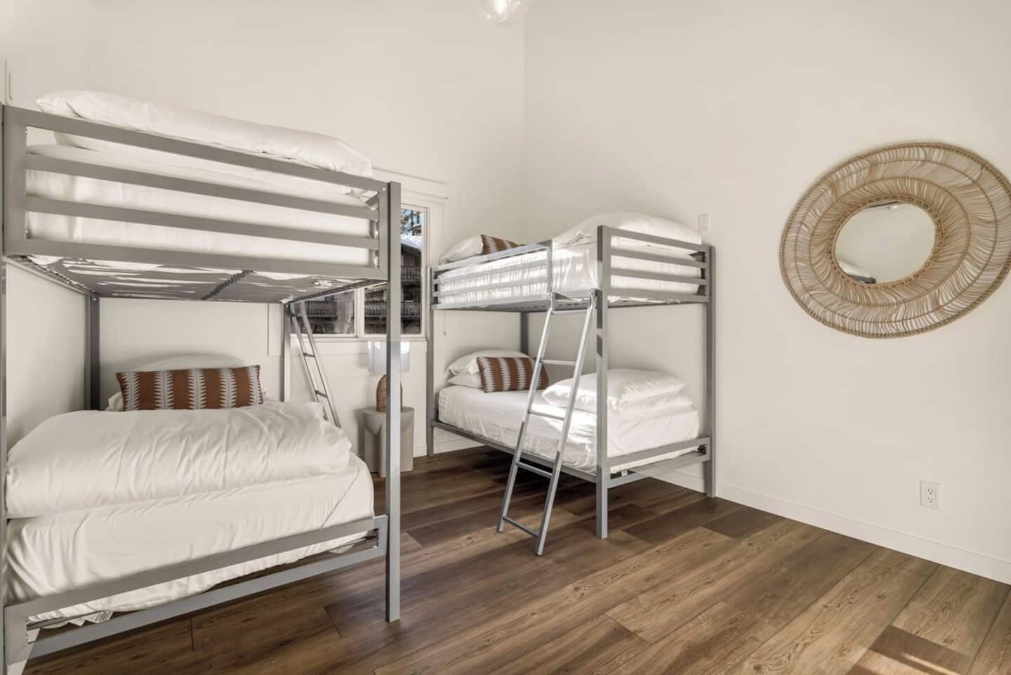 Una habitación con literas, una escalera, una mesita y un espejo redondo en la pared.