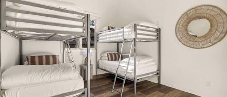 Una habitación con literas, una escalera, una mesita y un espejo redondo en la pared.