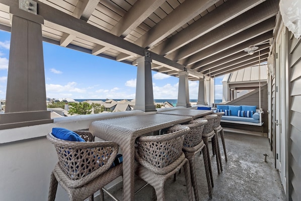 Eine Terrasse im Freien mit Korbmöbeln und Blick auf den Ozean.