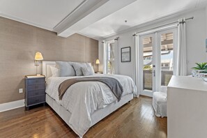 A bedroom with a bed, nightstand, lamp, and a view of the outside.