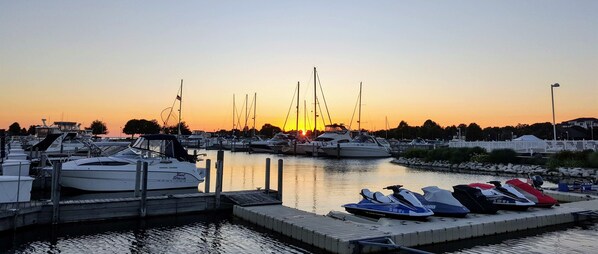 Ein Yachthafen im Abendlicht mit vertäuten Booten und Jet-Skis am Steg.