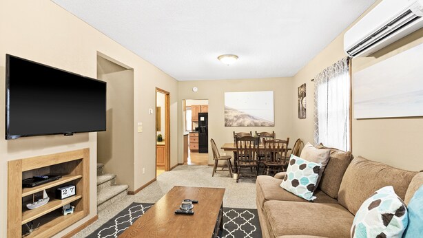 A living room with a flat-screen TV, a wooden coffee table, a beige sofa with patterned cushions, and a dining area with a wooden table and chairs. -  ⚓️Close to Duluth! Close to Lake Superior! Whole house! Centrally located! ⚓️ (Superior)