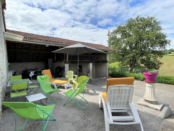 An outdoor patio with green and white chairs, a table, and a large umbrella. - LASSEGUES - CASTETNER (CASTETNER)