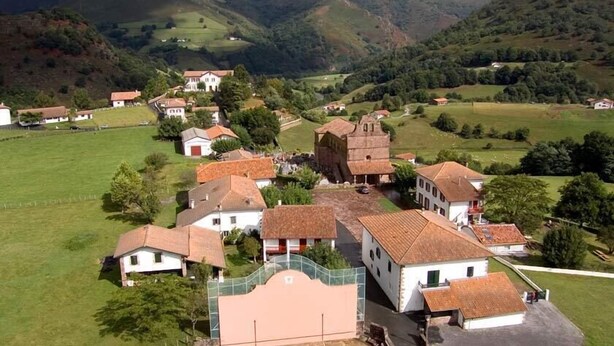 Un pueblo con arquitectura tradicional, que incluye una torre destacada y varias casas con techos de tejas rojas.