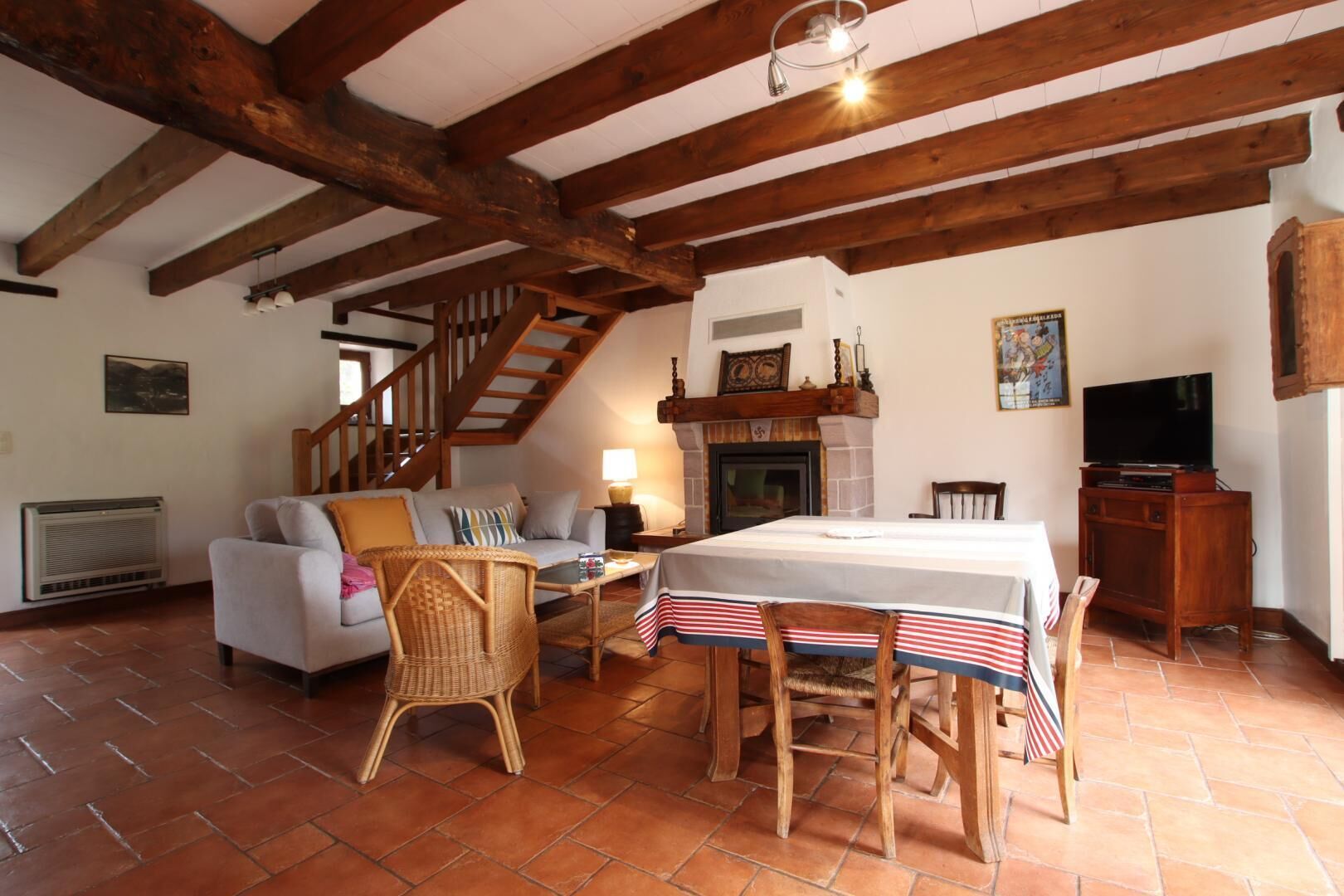 A cozy living room with a fireplace, a dining table with a flag, and a staircase leading to an upper level.