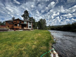 Una casa de dos pisos con terraza y vista al río.