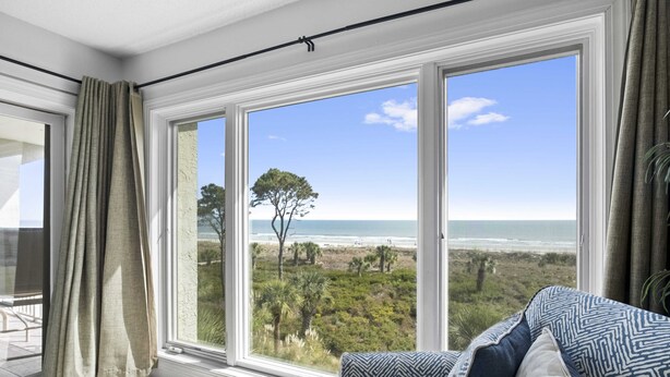 Una habitación con un amplio ventanal que ofrece vistas a la playa y al océano.