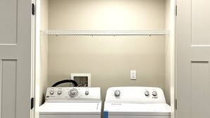A laundry room with two front-loading washing machines and a dryer. - New two-bedroom legal suite with parking (White Rock)