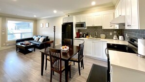 A modern apartment with a dining area, kitchen, and living room. - New two-bedroom legal suite with parking (White Rock)