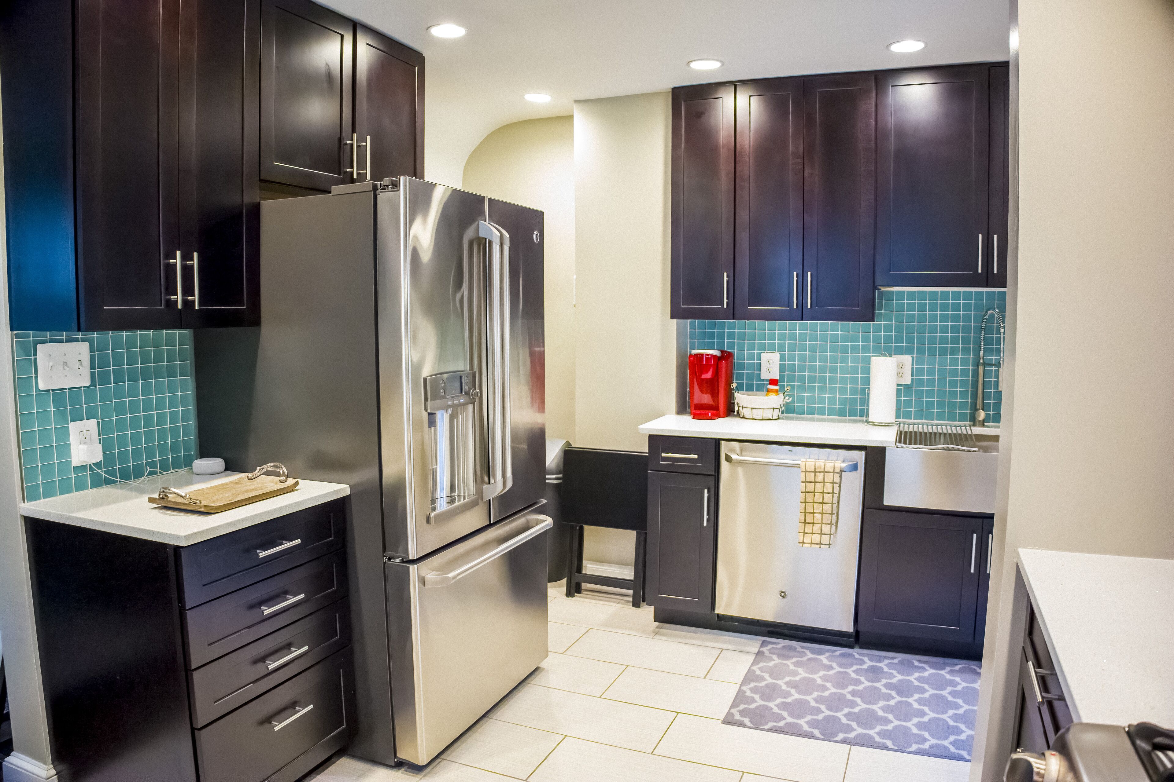 A modern kitchen with dark cabinets, stainless steel appliances, and a tiled backsplash.