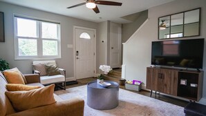 A living room with a sofa, a coffee table, a TV, and a staircase.