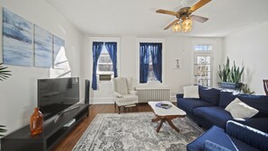 A living room with a TV, sofa, armchair, and a ceiling fan. - Walk Central. Museum district. Scott's Addition. 2BR - King and full bed.  (Richmond)