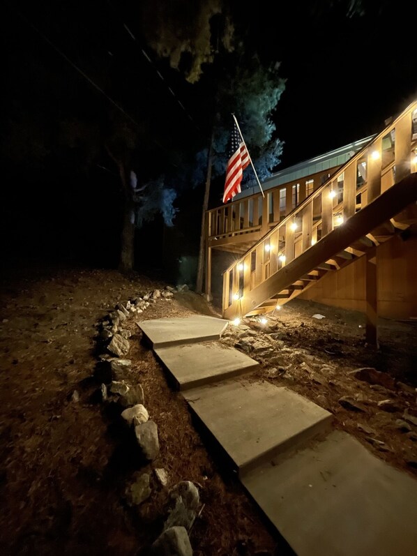 Une vue nocturne d’un escalier en bois menant à un bâtiment sur lequel flotte un drapeau américain.