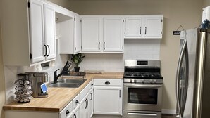 Una cocina moderna con armarios blancos, electrodomésticos de acero inoxidable y encimera de madera.