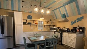 A compact kitchen with a dining area, featuring a refrigerator, microwave, stove, and a coffee maker.