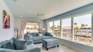 A spacious living room with a large window, a sectional sofa, and a view of a marina. - Boat Dock & Patio: Canal-Front St James City Home! (St. James City)