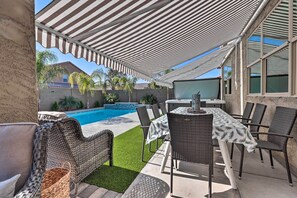 Um pátio externo com piscina, móveis de vime e uma área de refeições coberta.