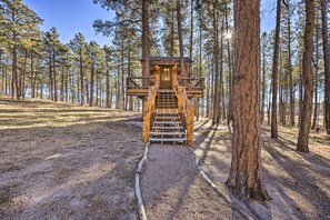 A wooden treehouse with a staircase leading up to it, surrounded by a forest. - CO Springs Apartment in the Pines w/ Treehouse! (Colorado Springs)