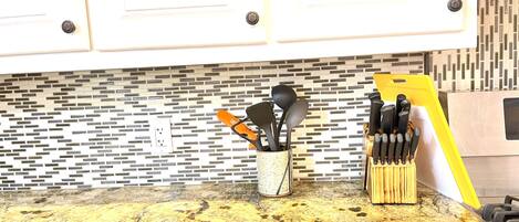 A kitchen counter with a granite top, a knife block, and a utensil holder.