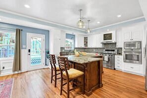 A modern kitchen with white cabinets, a central island, and stainless steel appliances.