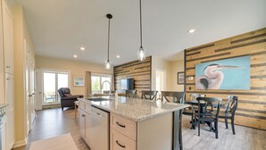 Eine moderne Küche mit Granit-Arbeitsplatte, Holzvertäfelung und einer Essecke mit schwarzen Stühlen und einem Tisch.