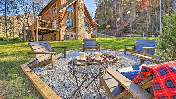 Eine Blockhütte mit einer Terrasse, Sitzgelegenheiten im Freien und einer Feuerstelle.