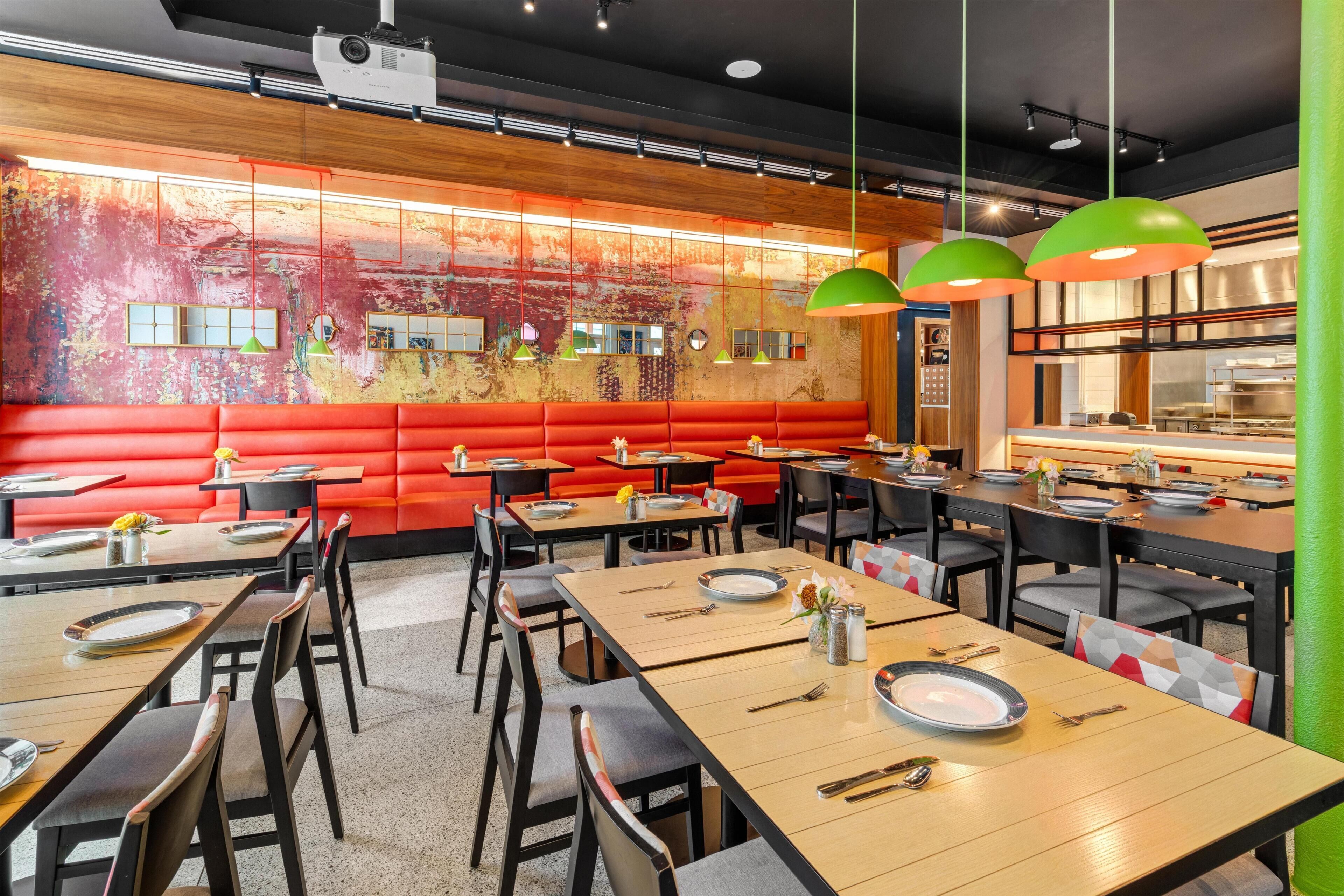 L’intérieur d’un restaurant, avec des banquettes, des tables et un coin bar.