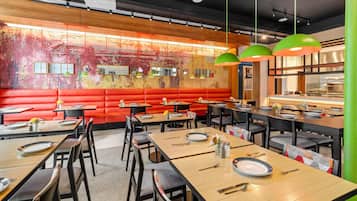 L’intérieur d’un restaurant, avec des banquettes, des tables et un coin bar.