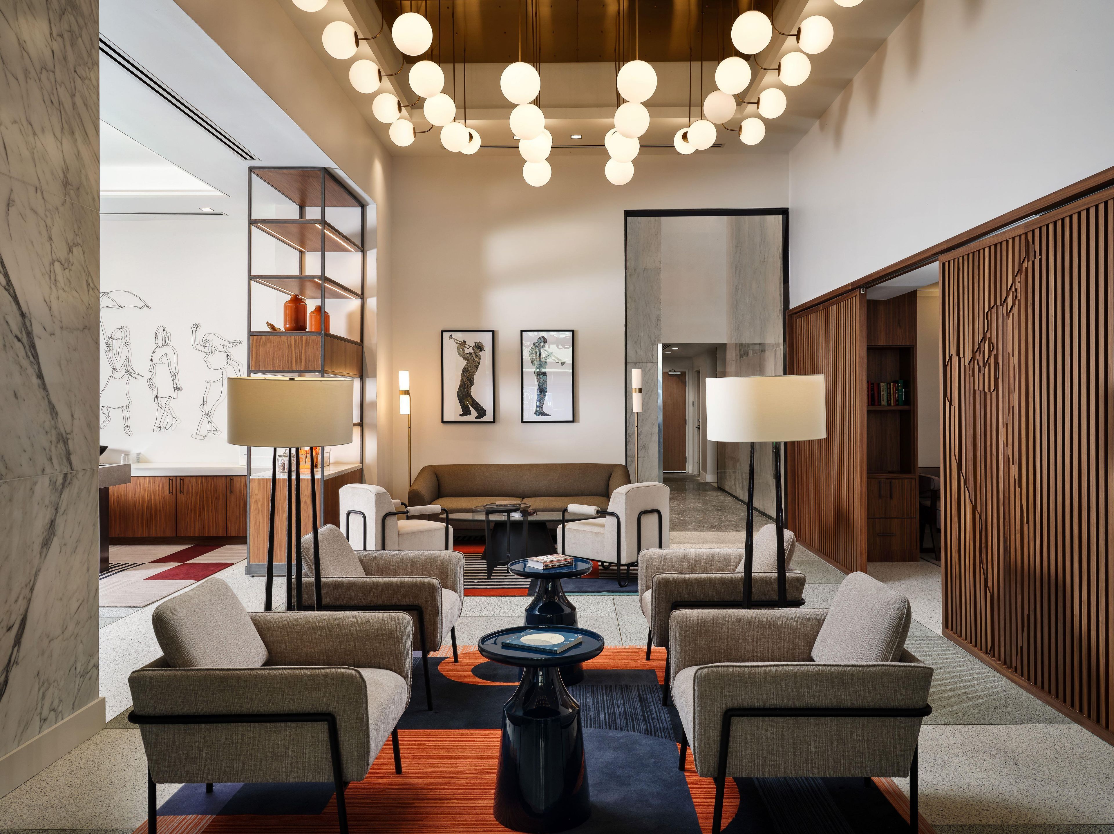 A modern lobby with a seating area, a large artwork, and a wooden partition.