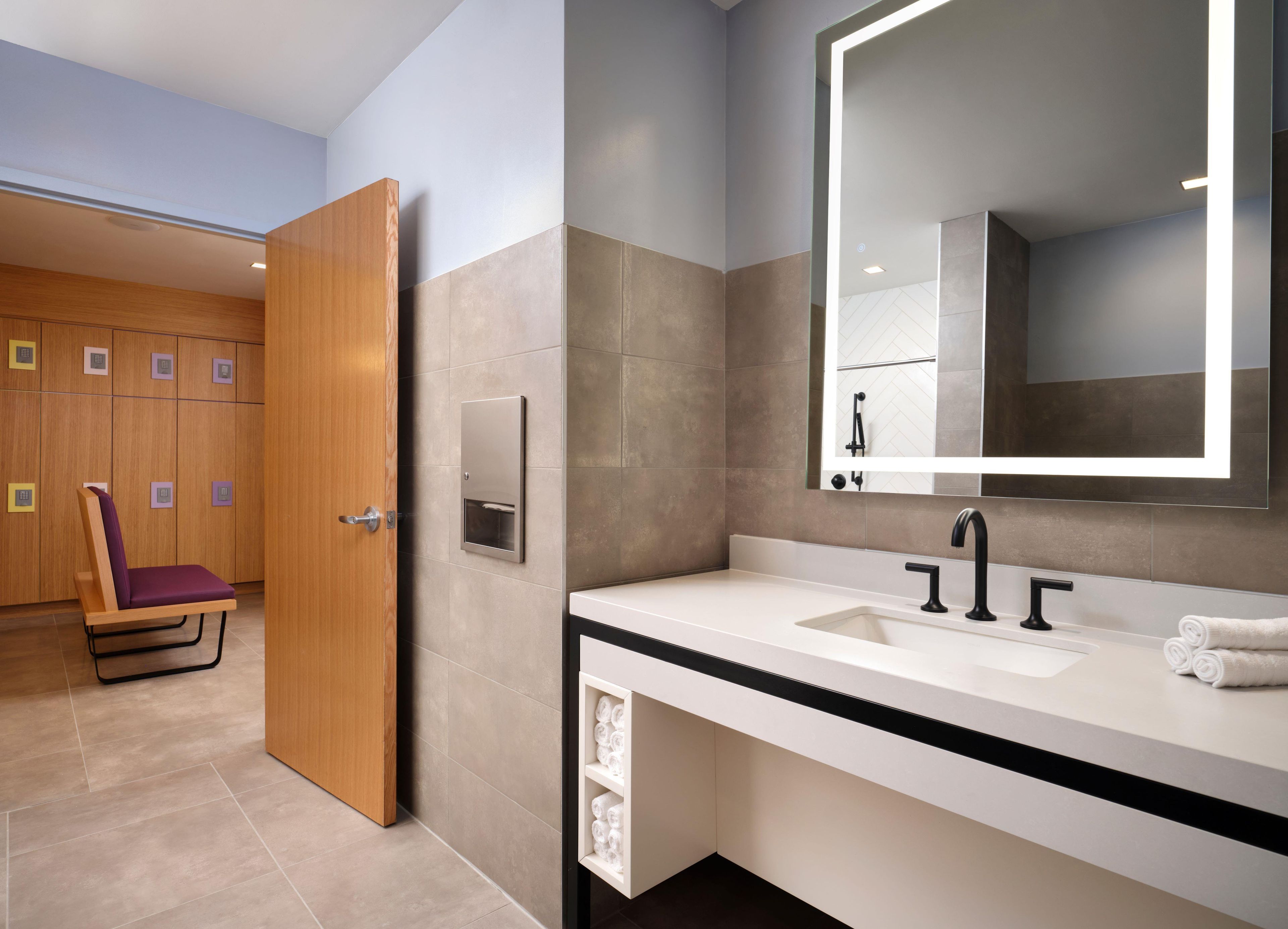 A modern bathroom with a large mirror, two sinks, and a towel rack.