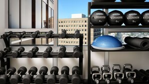 Une salle de sport équipée de divers poids, notamment des haltères et des balles lestées, disposés sur des supports.