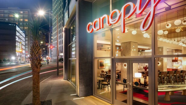 A modern building with a glass facade and a neon sign reading "canopy". - Canopy by Hilton New Orleans Downtown (New Orleans)