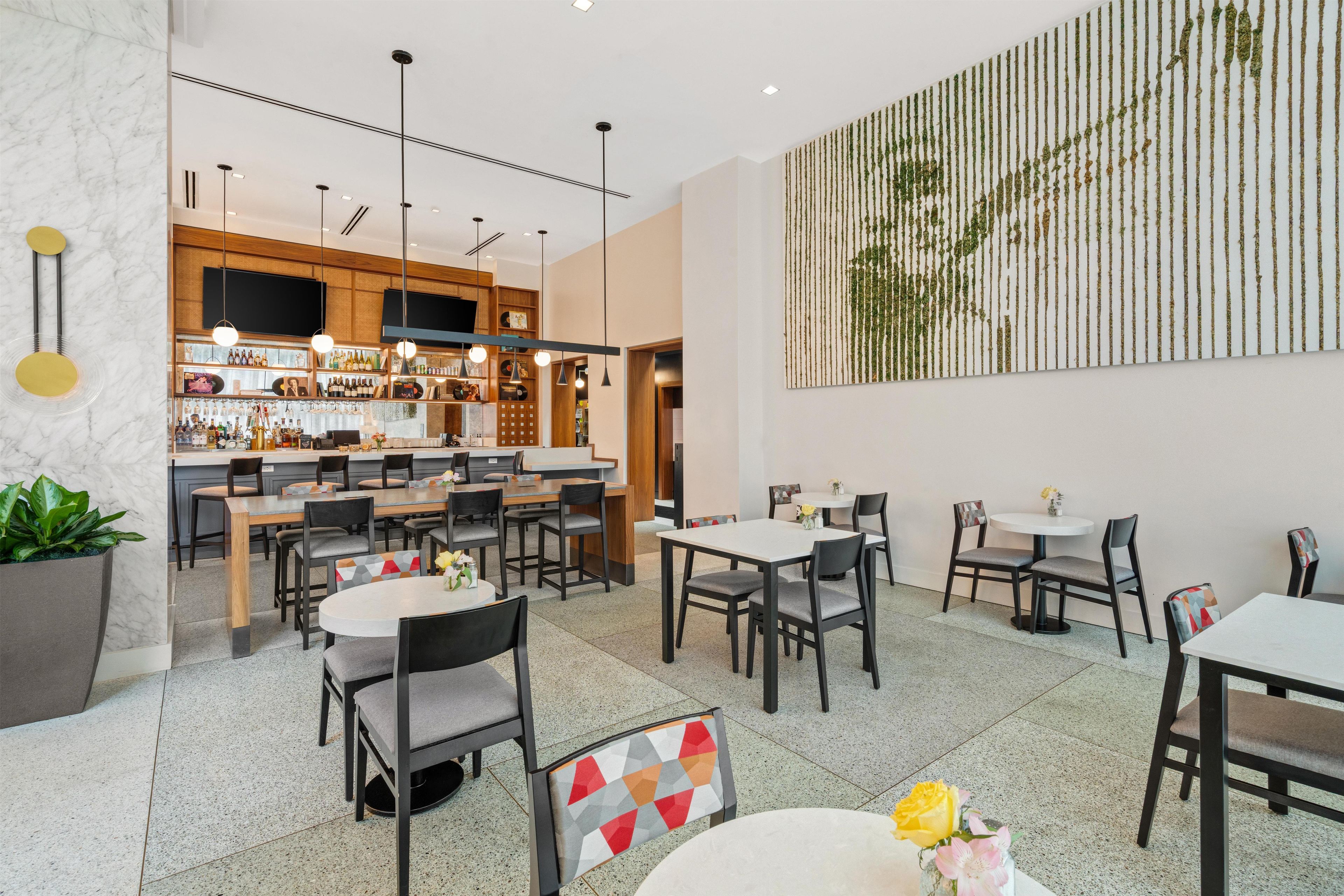A modern restaurant with a bar area, multiple seating options, and a decorative wall piece.