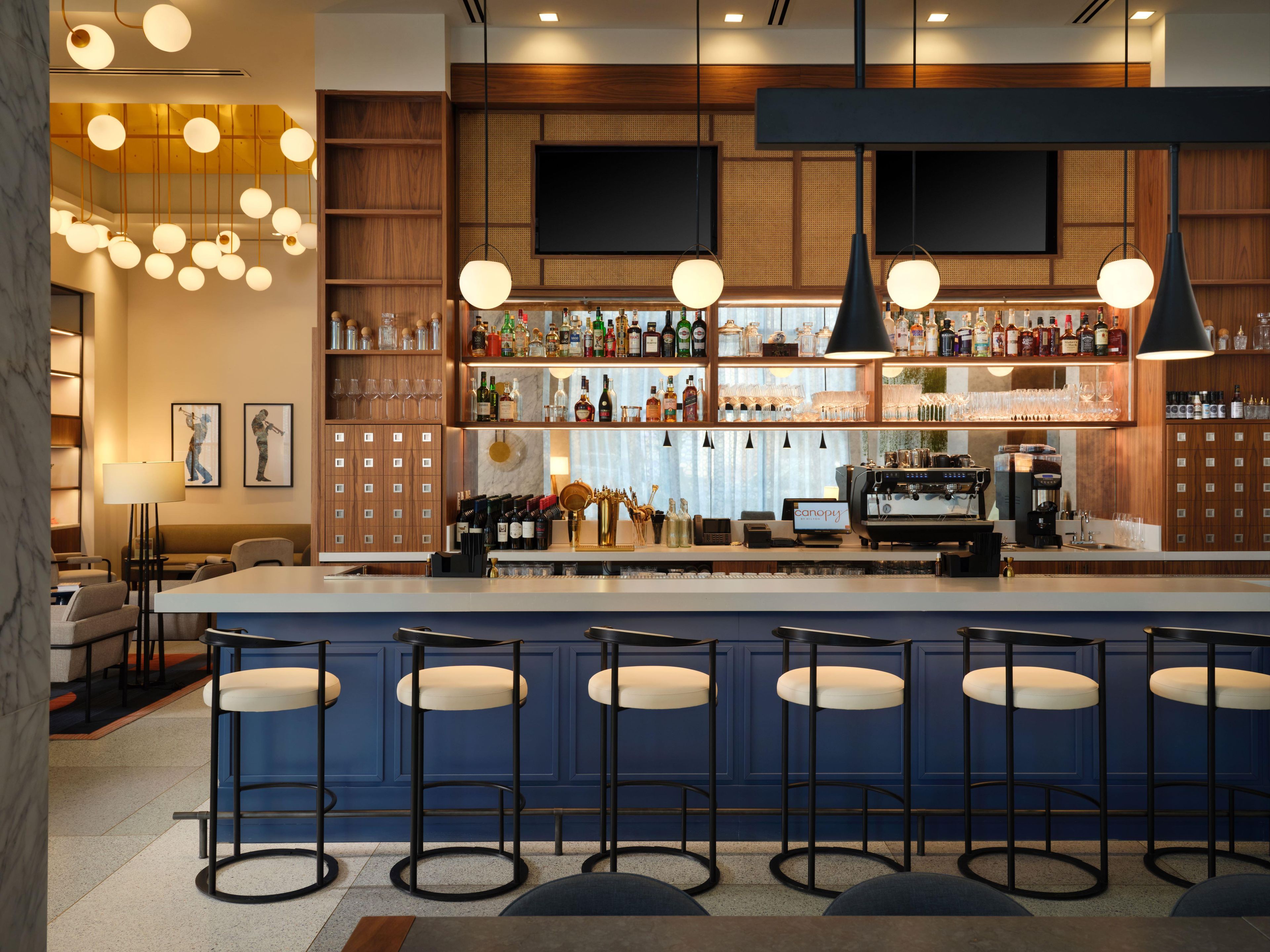 A bar area with a long counter, multiple stools, and a variety of bottles and glasses.