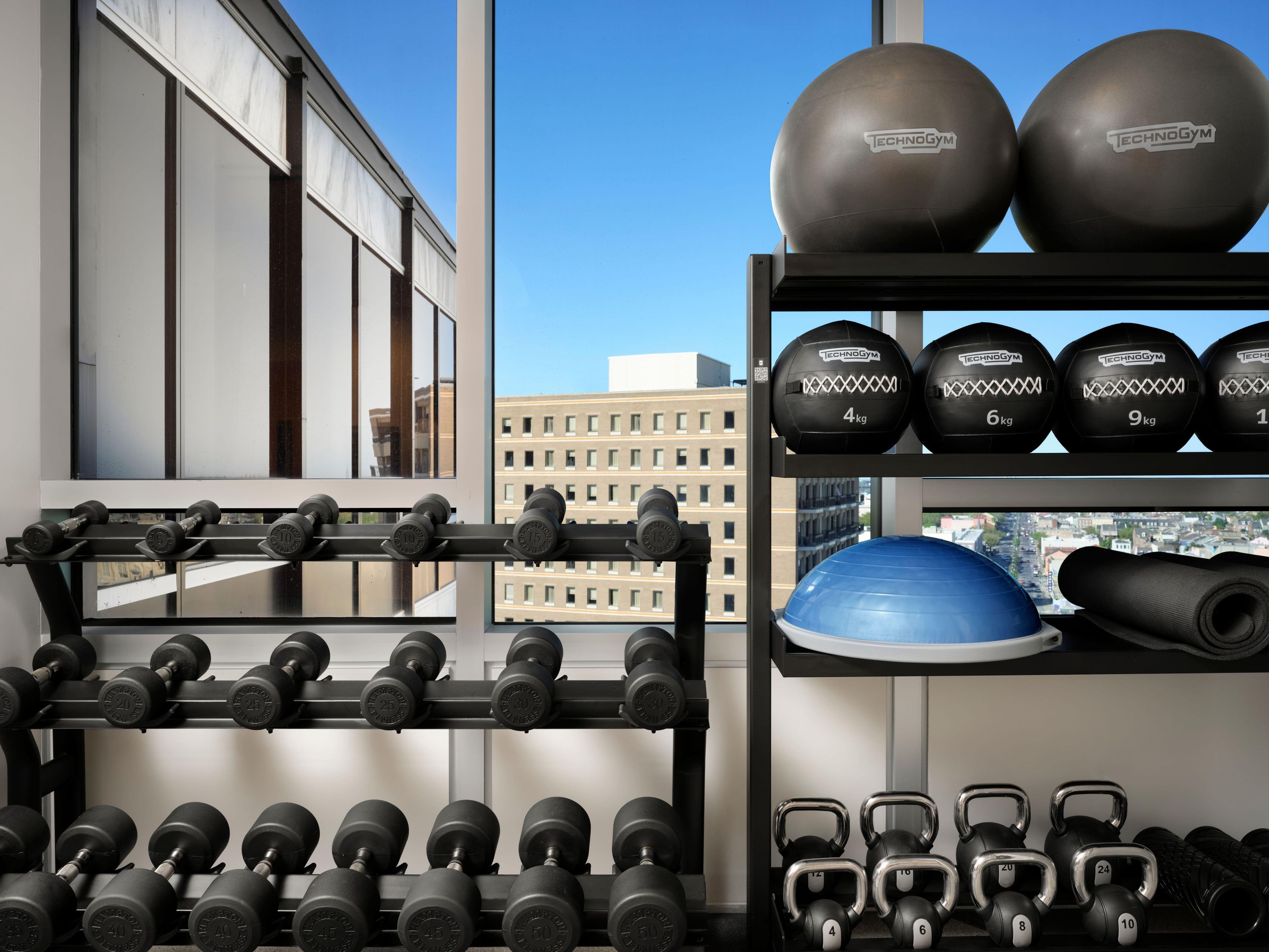 A gym with various weights and exercise equipment, including dumbbells, kettlebells, and medicine balls.