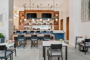 Un área de bar moderna con mostrador, asientos y una variedad de botellas y discos.