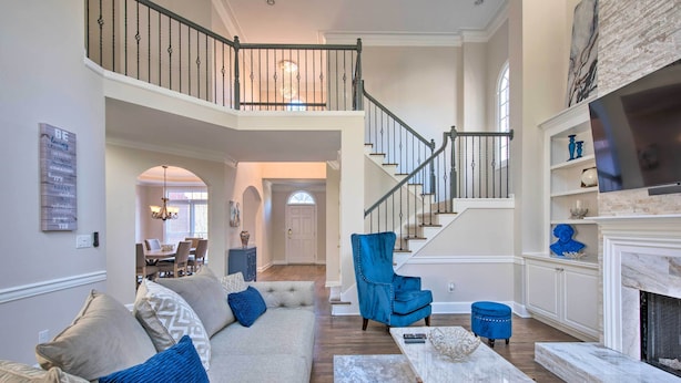 A spacious living room with a high ceiling, a staircase, and a fireplace. - Updated Mableton Home ~ 14 Miles to Downtown ATL! (Mableton)