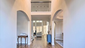 A spacious hallway with wooden flooring, a staircase leading to a balcony, and a seating area with a sofa and a coffee table. - Updated Mableton Home ~ 14 Miles to Downtown ATL! (Mableton)