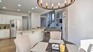 A modern kitchen with stainless steel appliances, a dining area with a round table, and a staircase leading to an upper level. - Updated Mableton Home ~ 14 Miles to Downtown ATL! (Mableton)