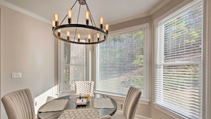 A dining area with a round table, beige chairs, and a chandelier. - Updated Mableton Home ~ 14 Miles to Downtown ATL! (Mableton)