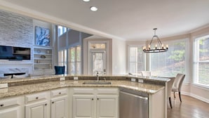 A modern kitchen with granite countertops, white cabinetry, a built-in dishwasher, and a large island. - Updated Mableton Home ~ 14 Miles to Downtown ATL! (Mableton)