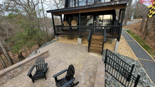 A modern house with a deck, two Adirondack chairs, and a stone fire pit. - Vintage Waterfront A Frame- Hideaway On The Bay (Lusby)