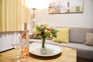 A table with a bottle of rose wine, two wine glasses, and a vase with flowers.