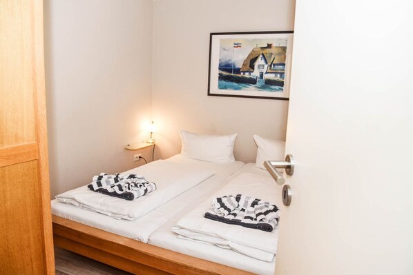 A hotel room with a bed, a nightstand, a lamp, and a framed picture on the wall.